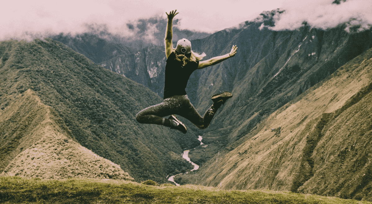 A woman jumping in the air, looking happy.