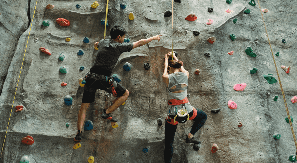 2 people doing rock climbing with the goal of going up.