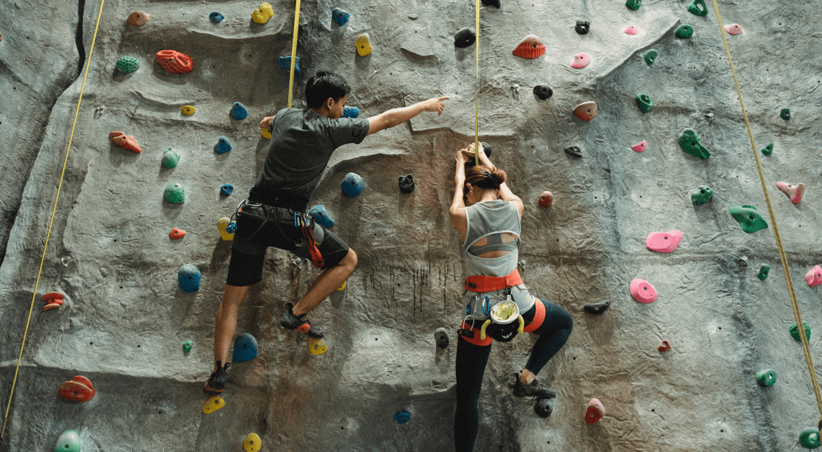 2 people doing rock climbing with the goal of going up.
